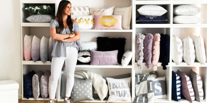 photo of Dormify's Amanda Zuckerman standing in front of a shelf containing an assortment of pillows