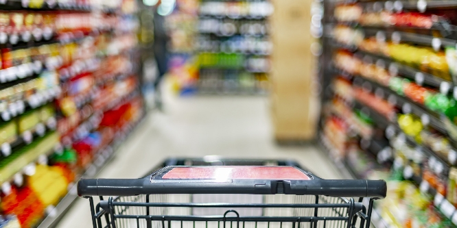 A shopping cart by a store shelf in a supermarket