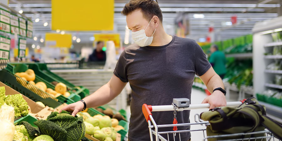 Man wearing disposable medical mask shopping in supermarket during coronavirus pneumonia outbreak