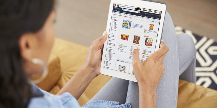 Woman Sitting On Sofa At Home Looking At Digital Tablet