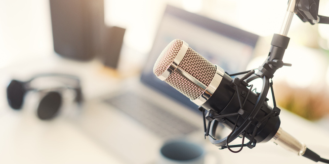 Close up of a studio microphone in focus, blurred background of a computer