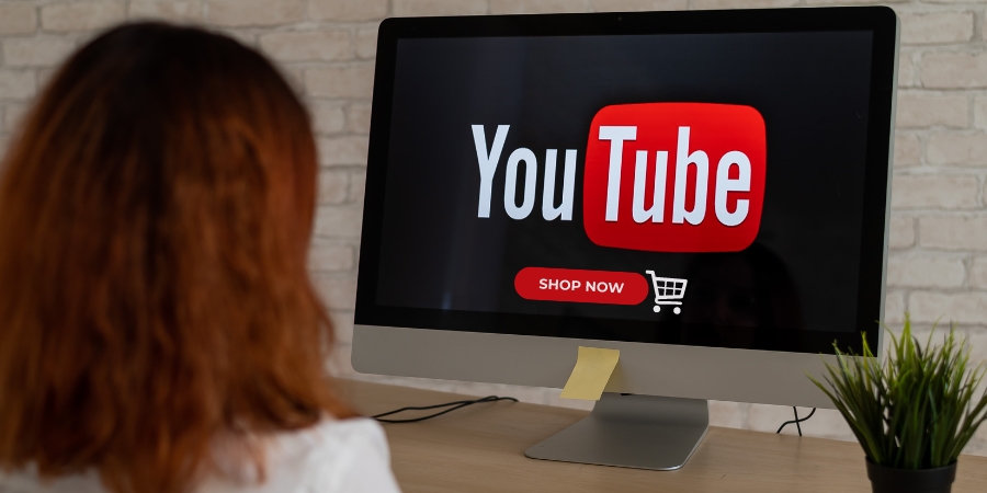 Woman looking at a computer screen with the YouTube logo above a "shop now" button